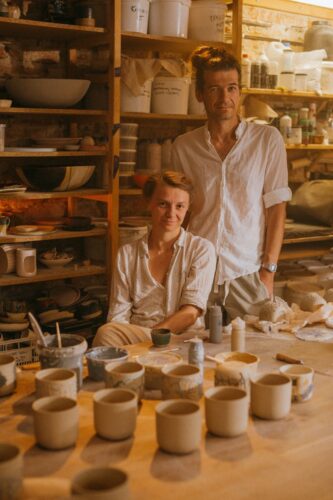 Two potters crafting ceramic pieces in a warm and intimate workshop environment.